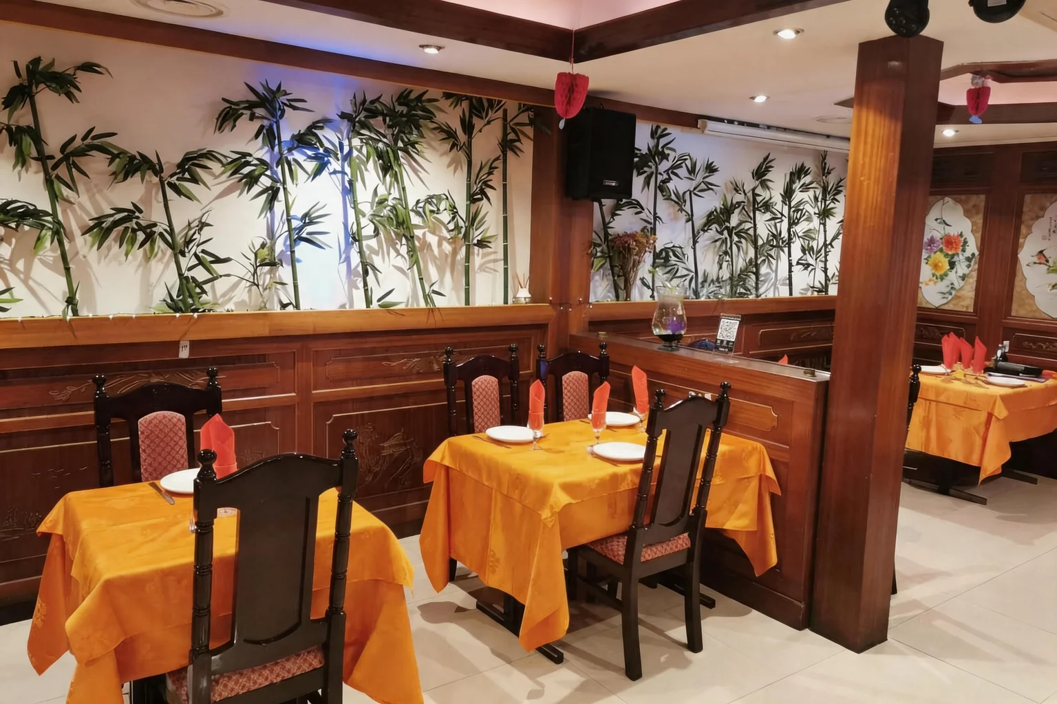 The dining room: orange tablecloths, dark wooden chairs, bamboo on the wall